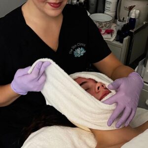 an esthetician at The Skin Clinics giving a client a custom facial